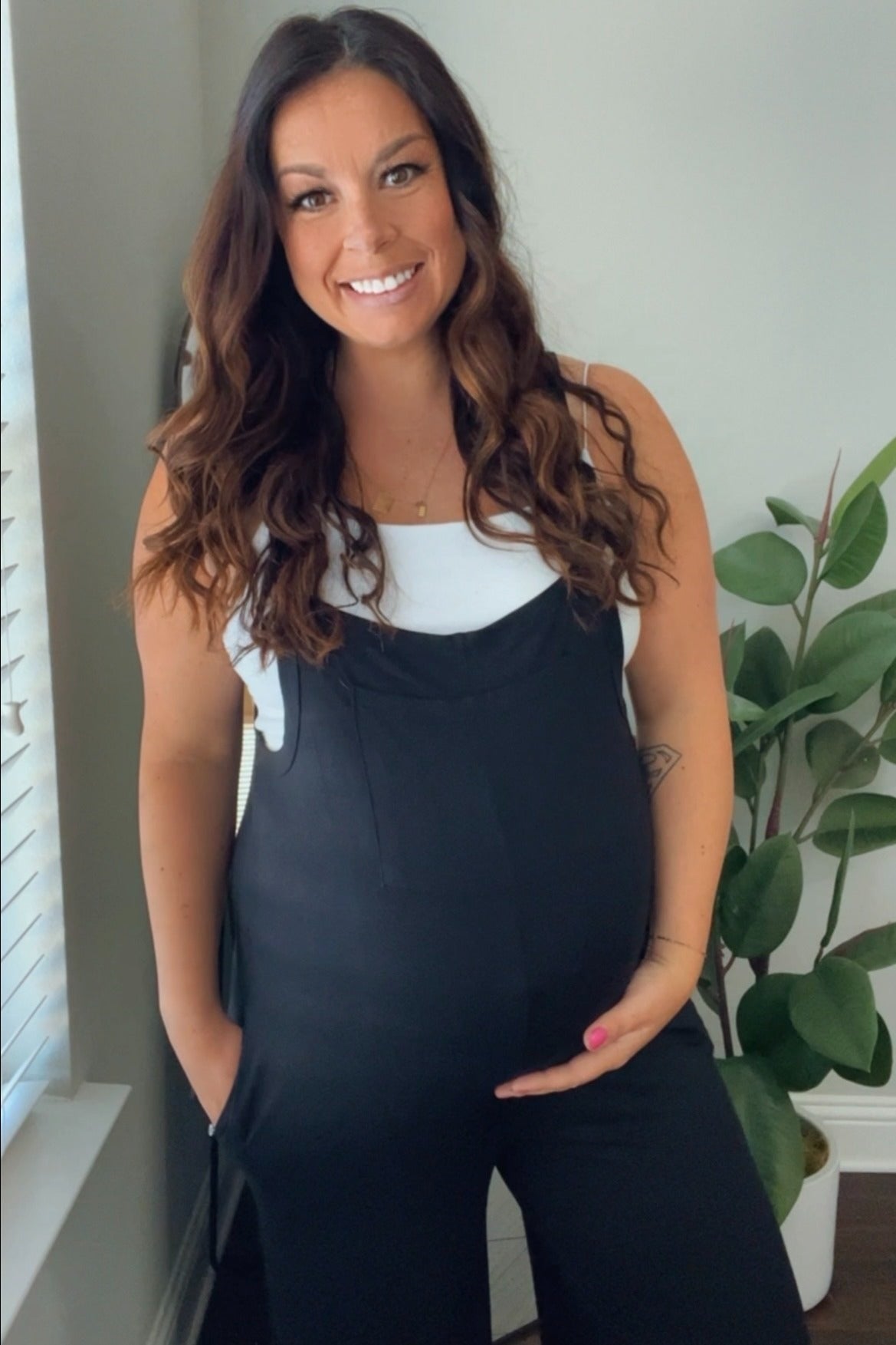 woman wearing a black maternity jumpsuit and holding her baby bump