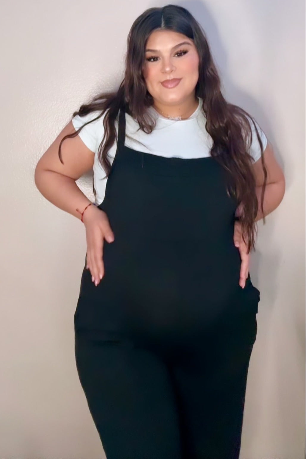 woman wearing a black maternity jumpsuit and showing her baby bump