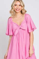 woman wearing a pink tie-front dress with flutter sleeves and a relaxed fit