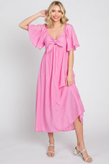 woman wearing a pink flutter sleeve maxi dress with a front knot detail