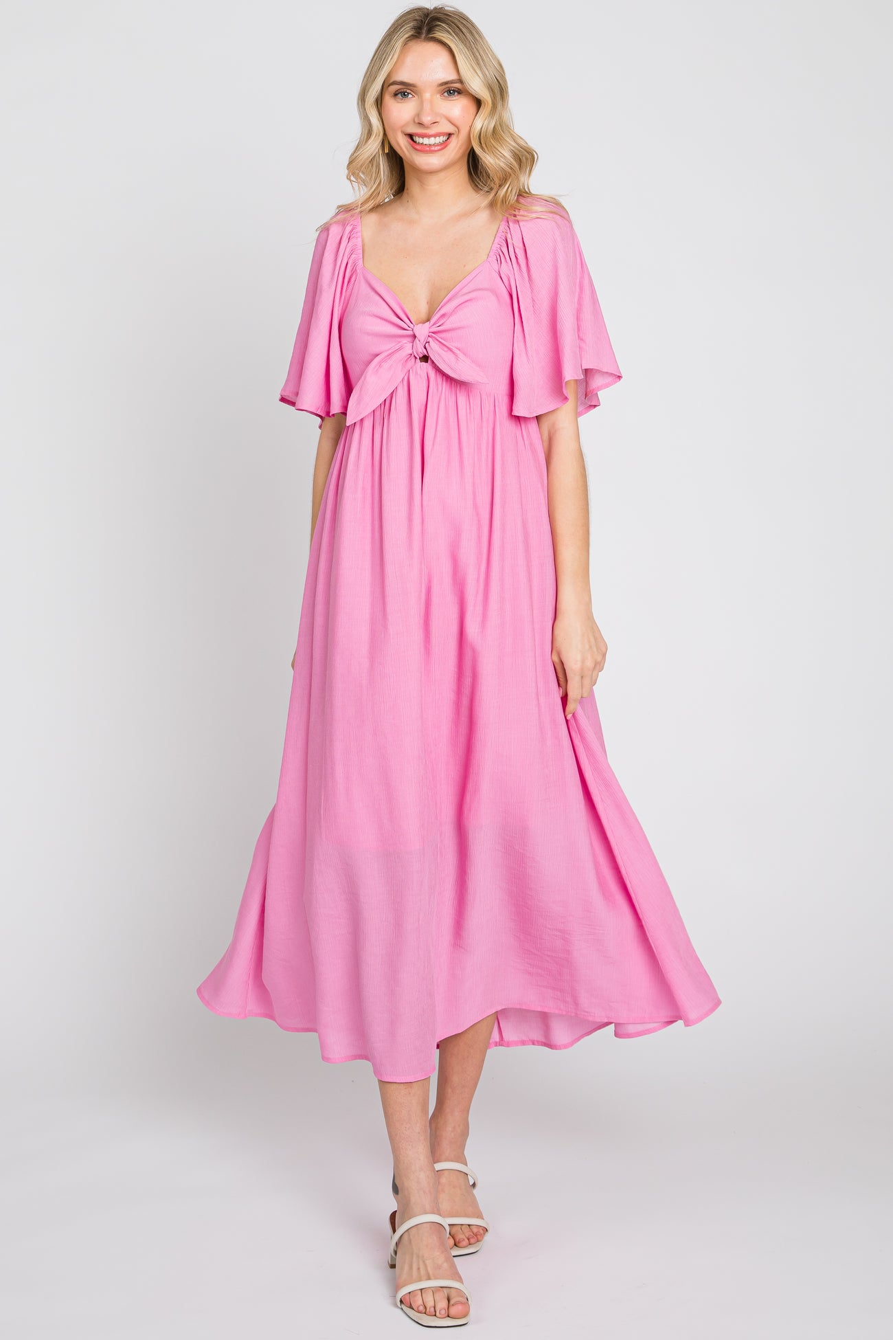 woman wearing a pink midi dress with flutter sleeves and a tied front detail