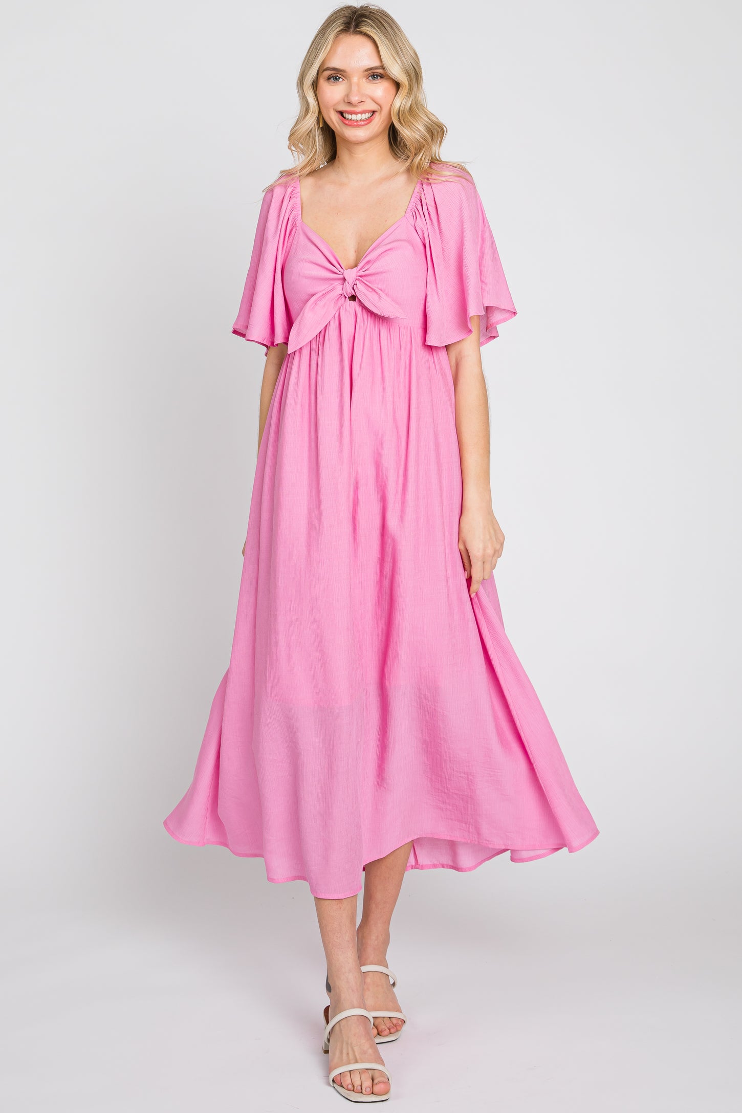 woman wearing a pink midi dress with flutter sleeves and a tied front detail