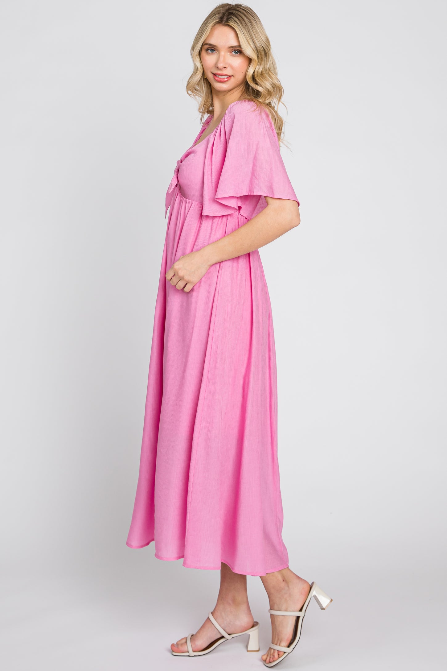 woman wearing a pink short sleeve maxi dress with a tie front and flowy silhouette