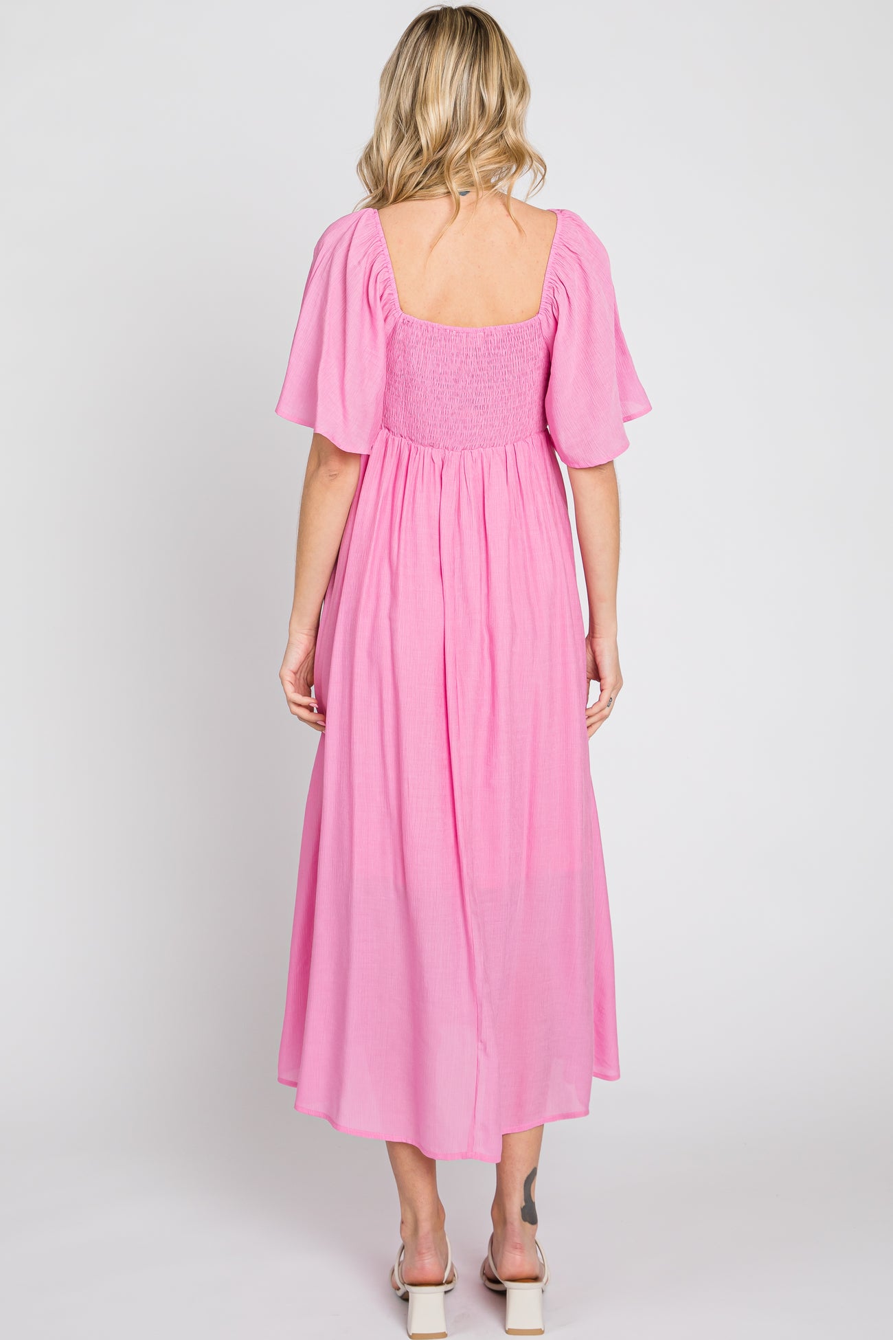woman wearing a pink smocked back maxi dress with short flutter sleeves and a square neckline