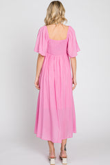 woman wearing a pink smocked back maxi dress with short flutter sleeves and a square neckline
