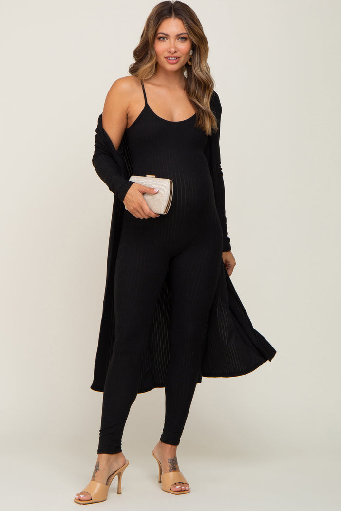 woman wearing a black ribbed maternity jumpsuit with a matching long cardigan and holding a clutch, showing baby bump