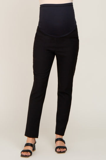 woman wearing black maternity dress pants with over the belly support band and black braided sandals
