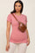 woman wearing a dusty rose short sleeve fitted top with a brown croc-embossed crossbody bag and light beige leggings