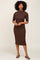 woman wearing a brown ribbed midi dress with short sleeves and a high neckline