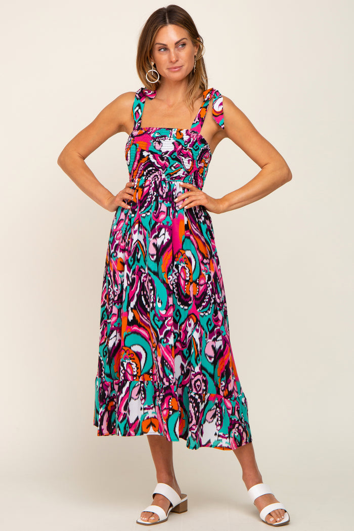woman wearing a colorful patterned midi dress with thick straps and a ruffled hem