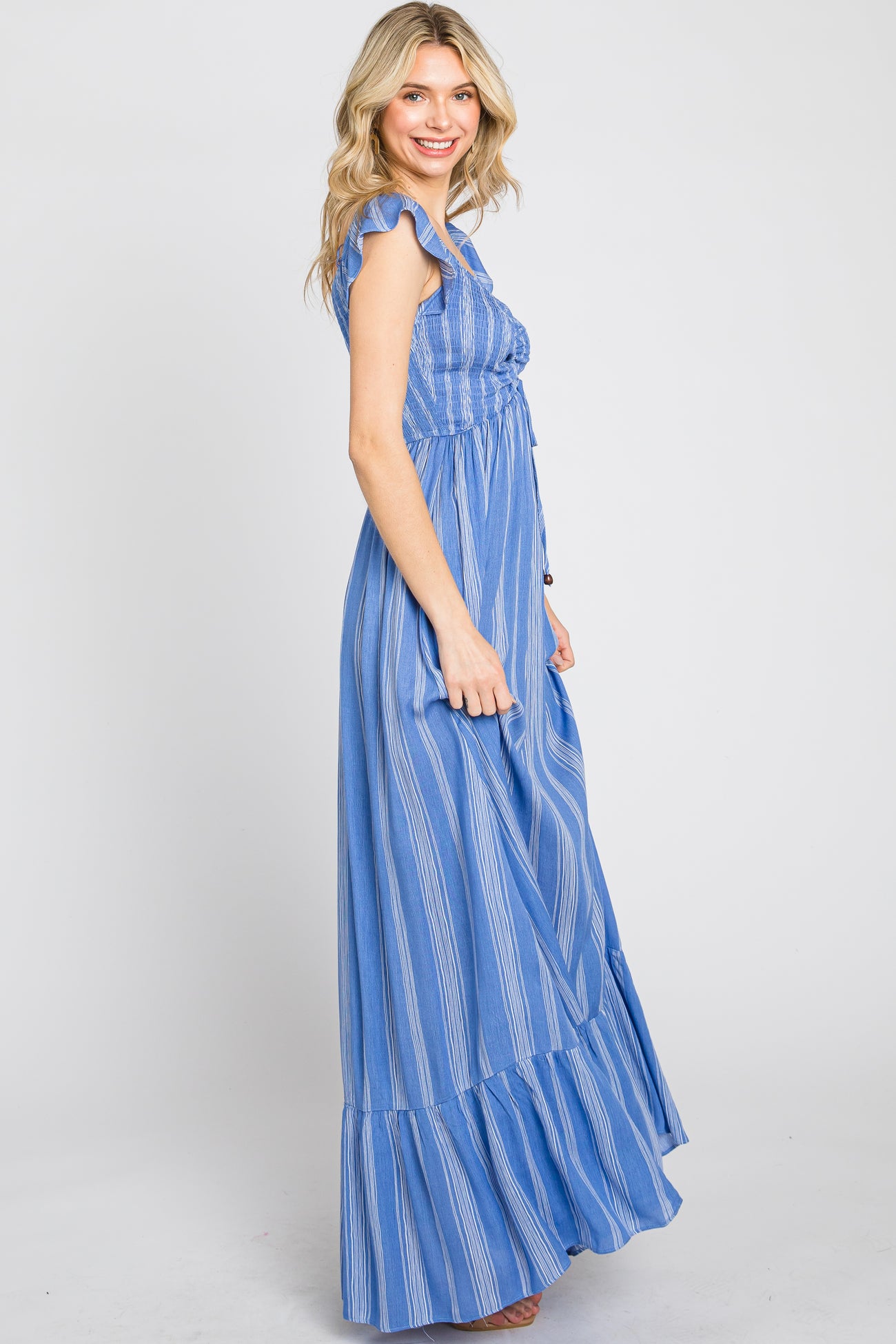 woman wearing a blue striped maxi dress with ruffle sleeves and a tiered hem, shown from the side
