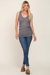 woman wearing a gray v-neck tank top and blue skinny jeans with brown slide sandals