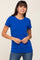 woman wearing a royal blue short sleeve t-shirt paired with jeans, standing with hands clasped in front of her