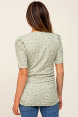 woman wearing a mint green floral print top with puff sleeves and a fitted silhouette, viewed from the back