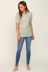 woman wearing a light green floral print puff sleeve top with ruched detailing and blue skinny jeans