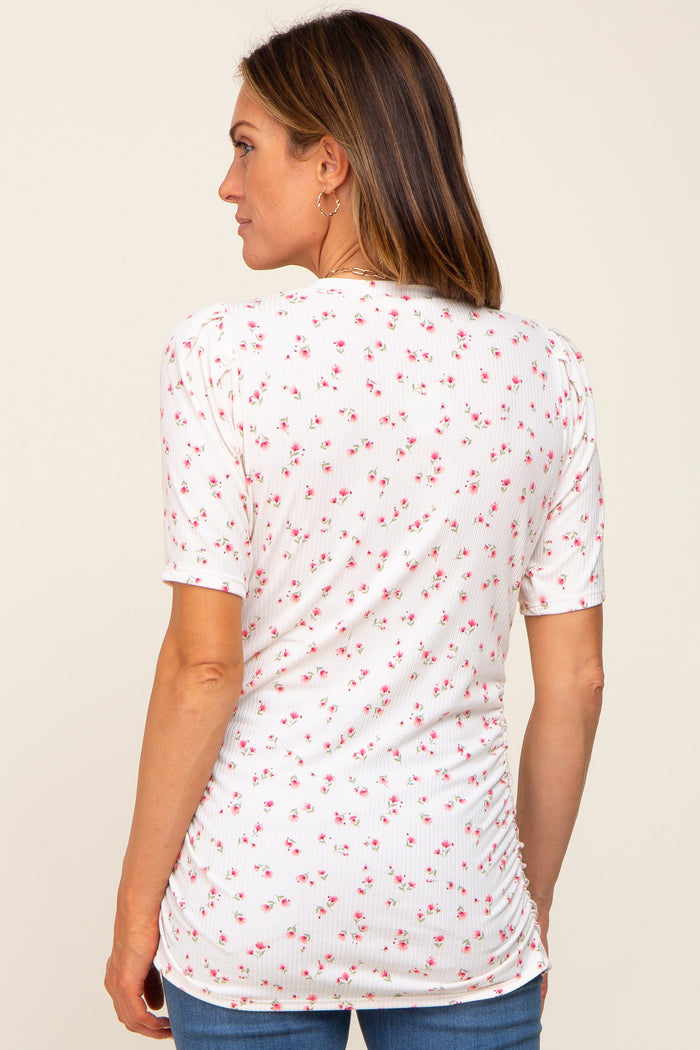 woman wearing a white short sleeve top with a floral print and gathered detail at the back