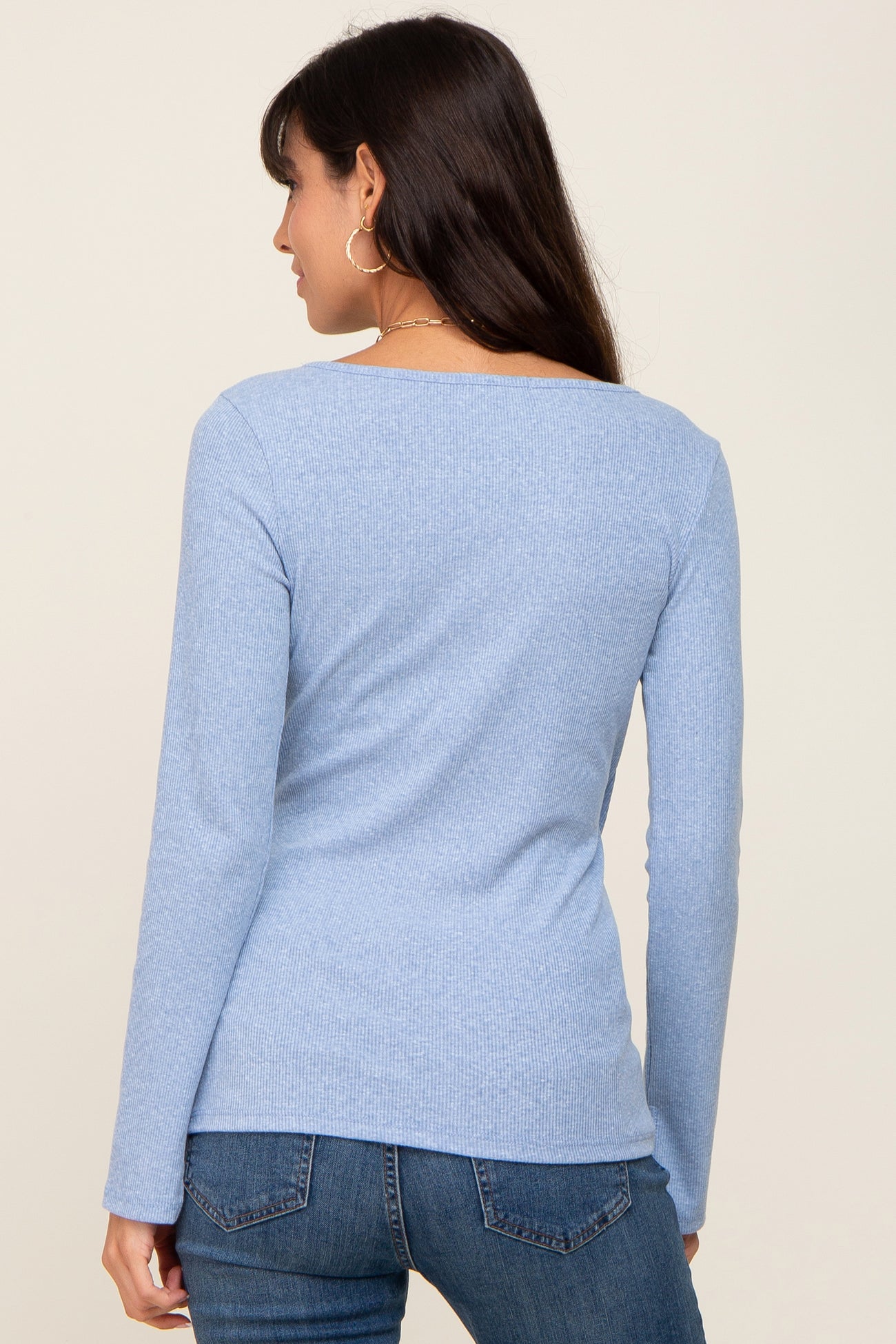 back view of a woman wearing a light blue long-sleeve ribbed top and denim jeans