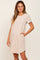 woman wearing a beige short sleeve t-shirt dress with rolled cuffs and side pockets