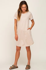 woman wearing a beige short sleeve t-shirt dress with pockets and olive green sandals