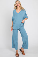 woman wearing blue v-neck short sleeve top and matching wide leg lounge pants with brown sandals