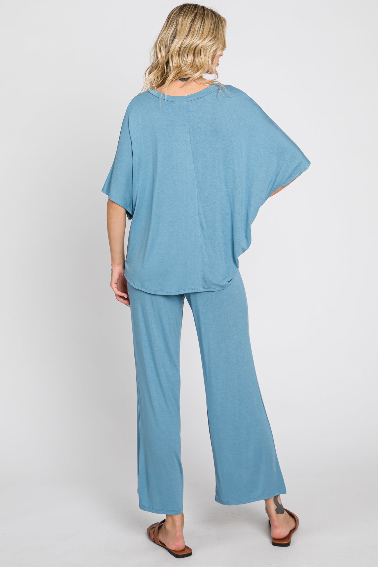 Back view of a woman wearing a dusty blue two-piece lounge set with wide-leg pants and a short-sleeve top