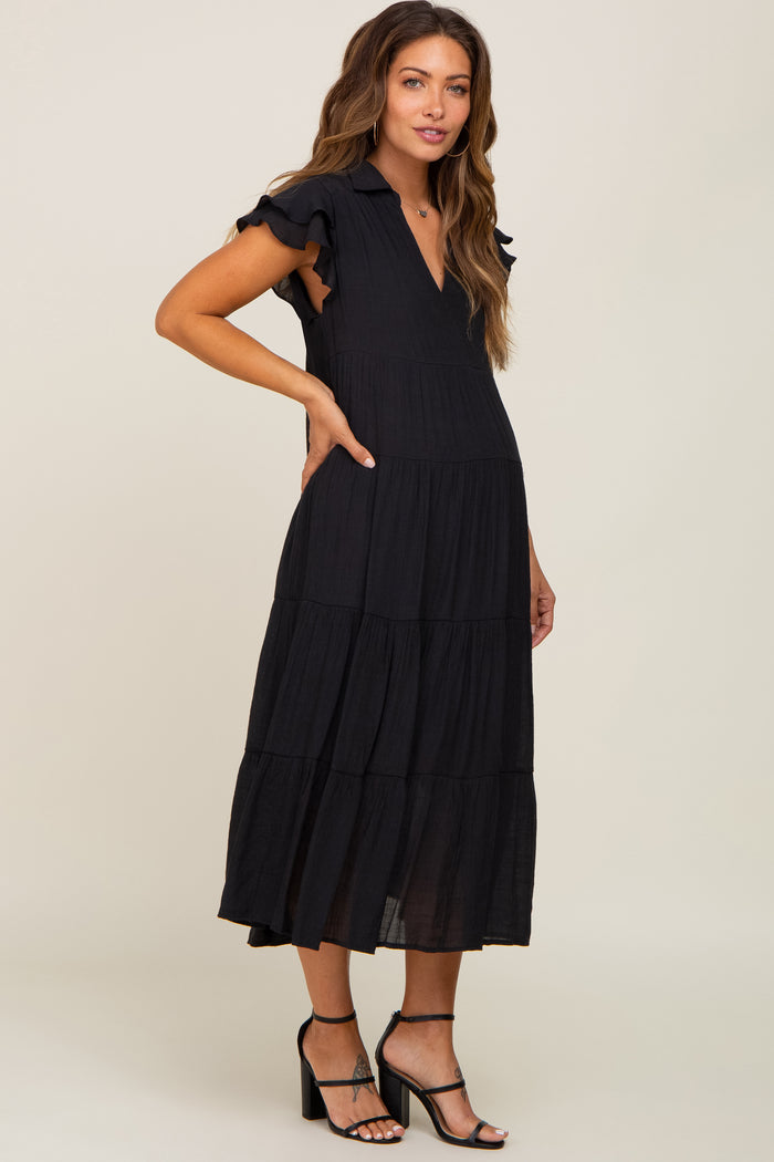 woman wearing a black tiered maternity midi dress with ruffle sleeves and black strappy heels