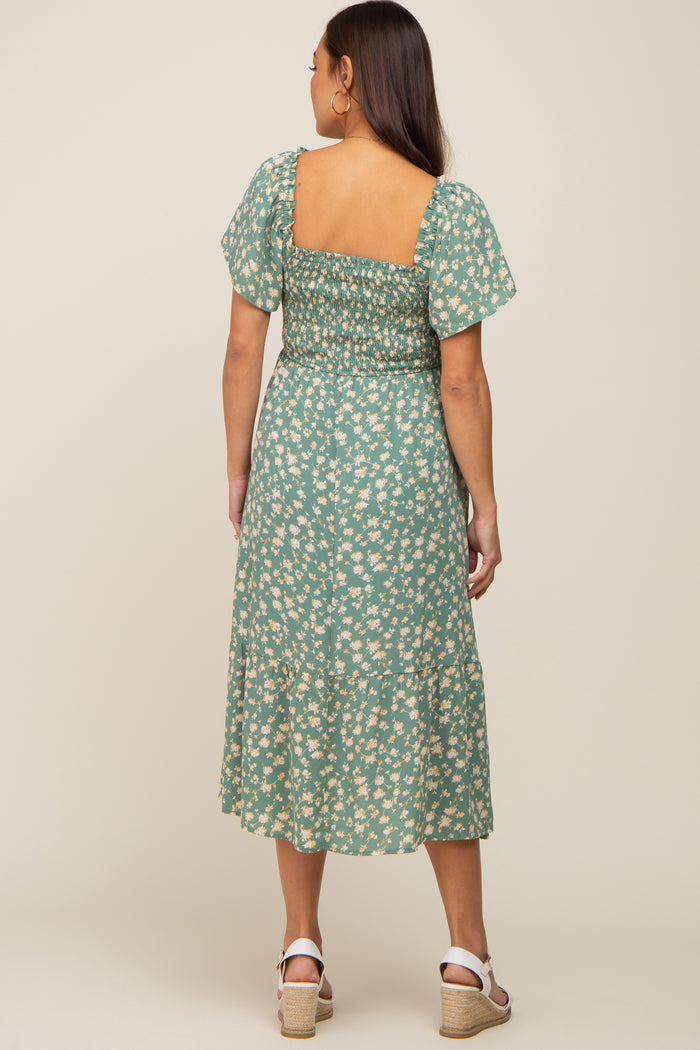 Woman from behind wearing a green floral midi dress with smocked back and white wedge sandals