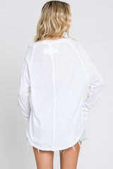 woman wearing a white long sleeve top with a scoop back and raw hem detail, shown from the back