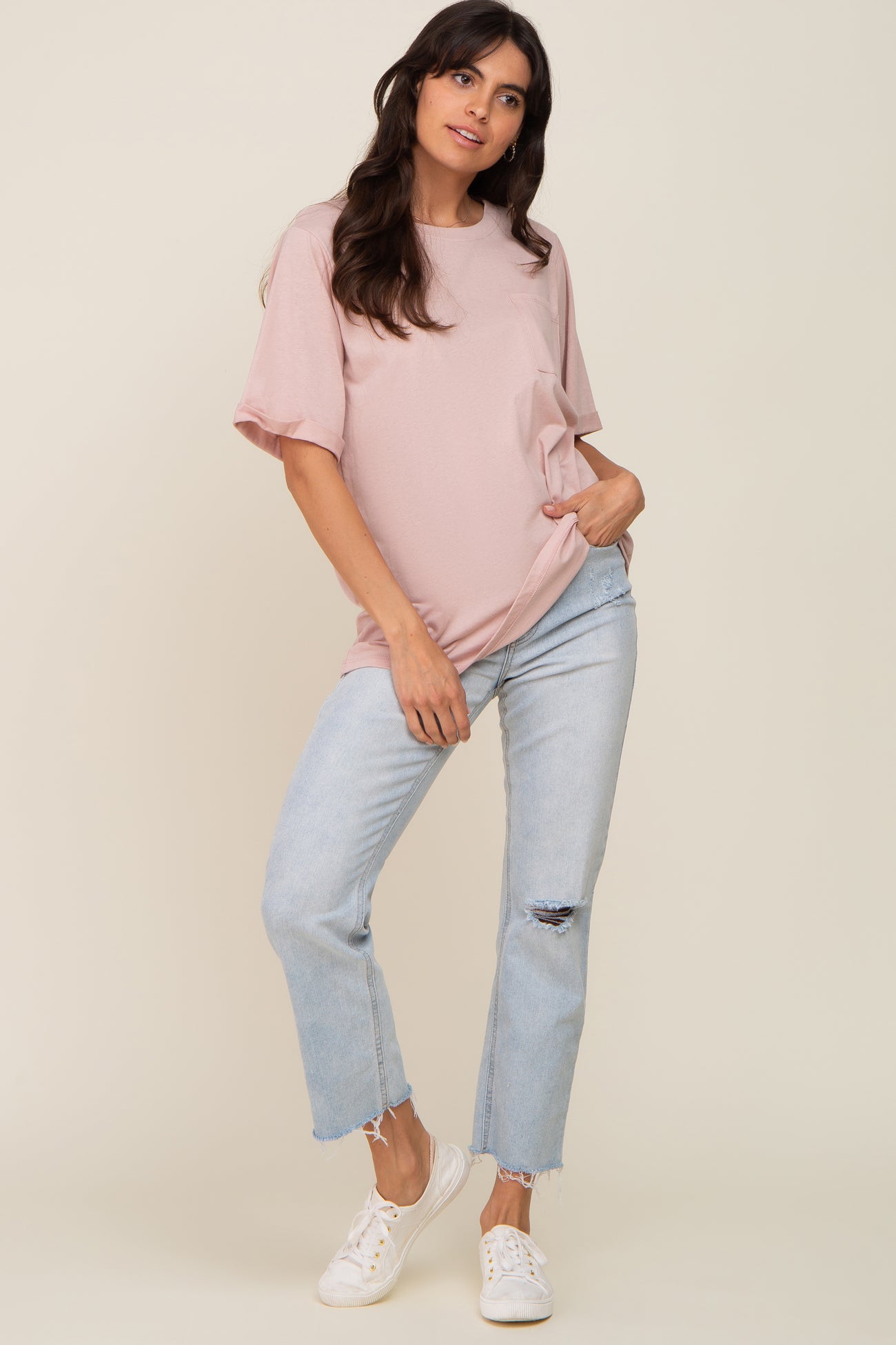woman wearing a blush pink oversized t-shirt with rolled sleeves and light blue distressed jeans
