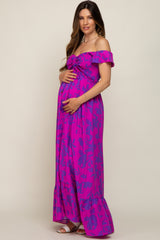 woman wearing a hot pink off-the-shoulder maternity maxi dress with floral pattern and holding her baby bump