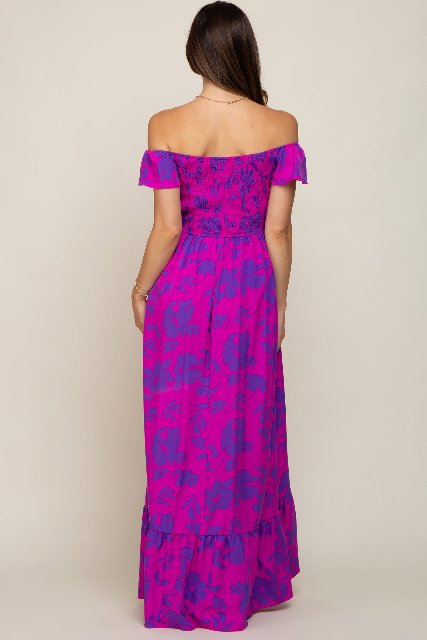 woman wearing a bright pink off-the-shoulder maternity maxi dress with floral print and ruffle hem