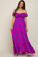 woman wearing a vibrant fuchsia off-the-shoulder maternity maxi dress with floral patterns and a cinched bodice