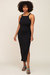 woman with afro hair wearing a black ribbed midi dress with side slit and patterned sandals