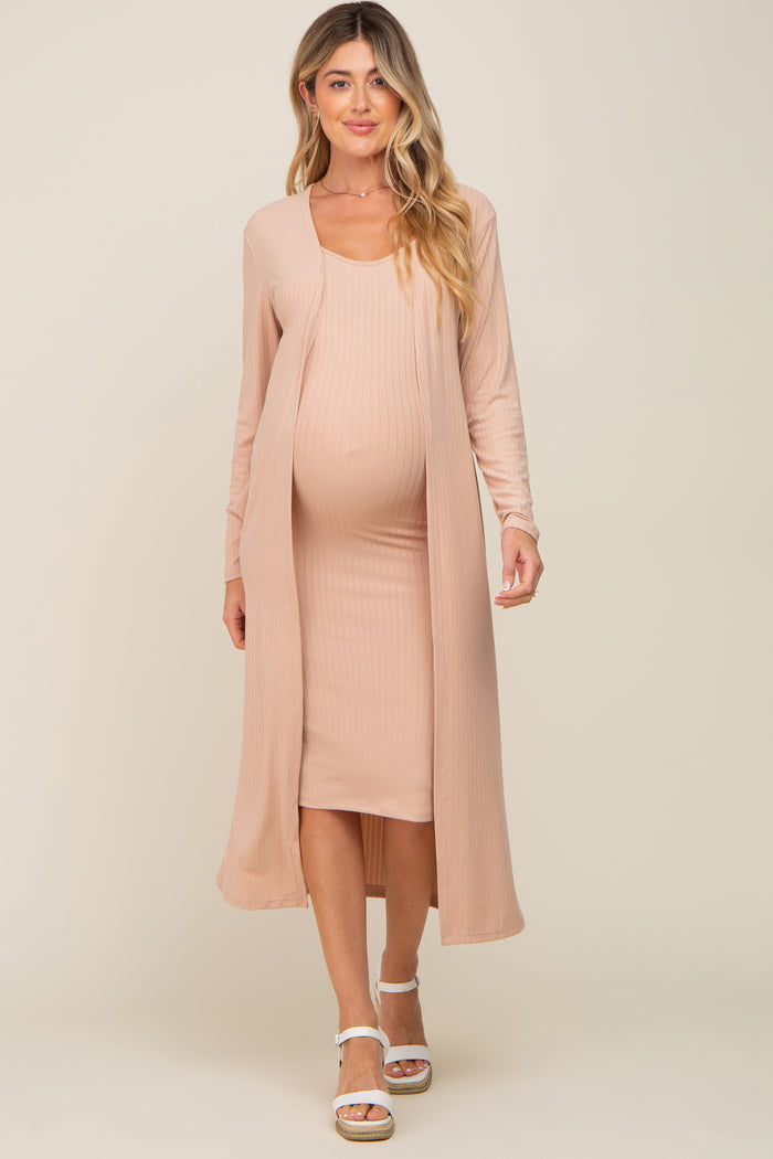 woman wearing a light peach maternity dress with a matching open-front cardigan and showing her baby bump