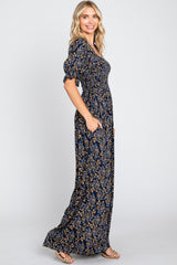 woman wearing a navy floral maxi dress with puff sleeves and pockets, standing sideways