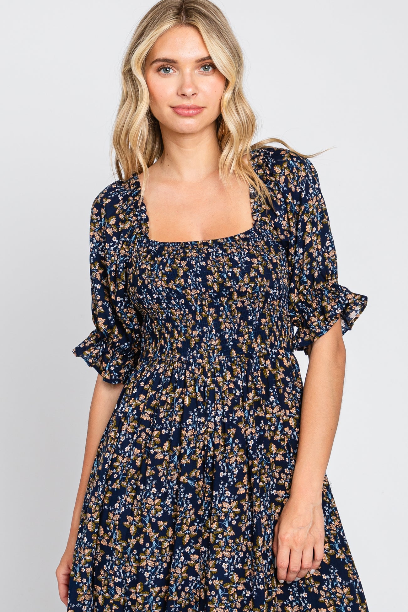 woman wearing a navy floral print dress with a square neckline and puffed sleeves