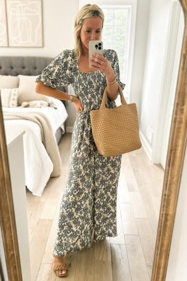 woman wearing a floral maxi dress with puff sleeves and holding a woven tote bag