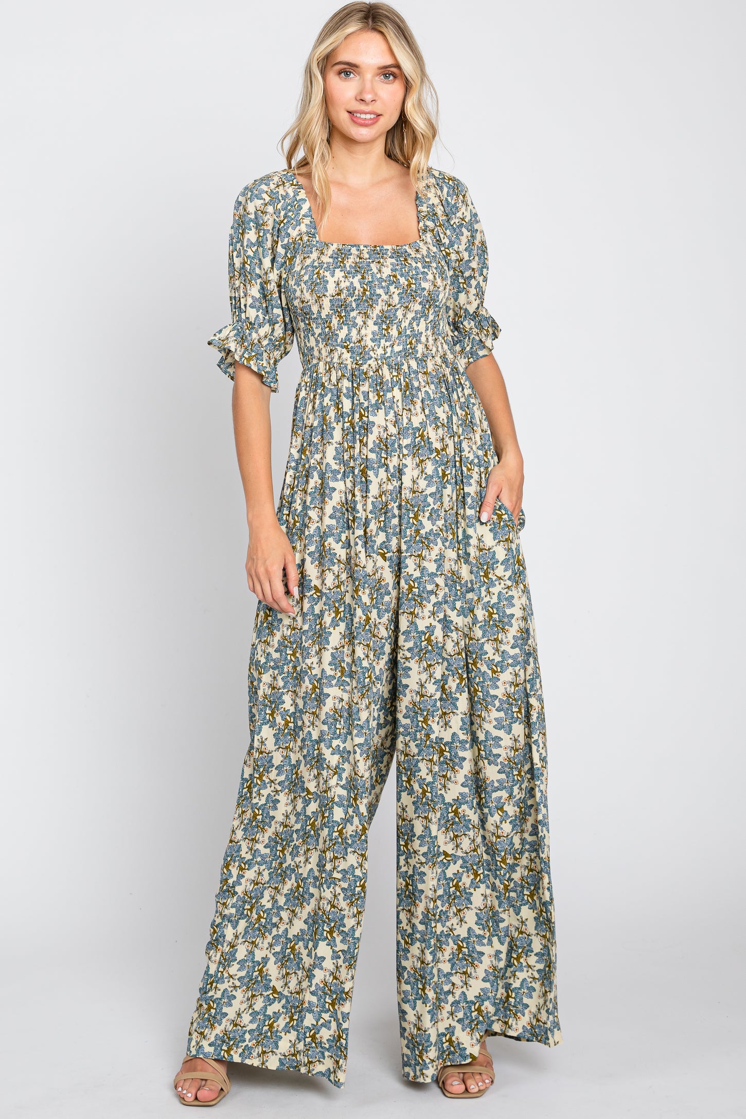 woman wearing a floral print maxi dress with a square neckline and puff sleeves, standing with hands in pockets