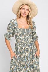 woman wearing a floral square neck dress with puff sleeves and pockets, paired with a wide-brimmed straw hat