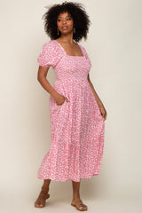 woman wearing a pink floral midi dress with puff sleeves and pockets