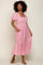 woman wearing a pink floral midi dress with puff sleeves and pockets