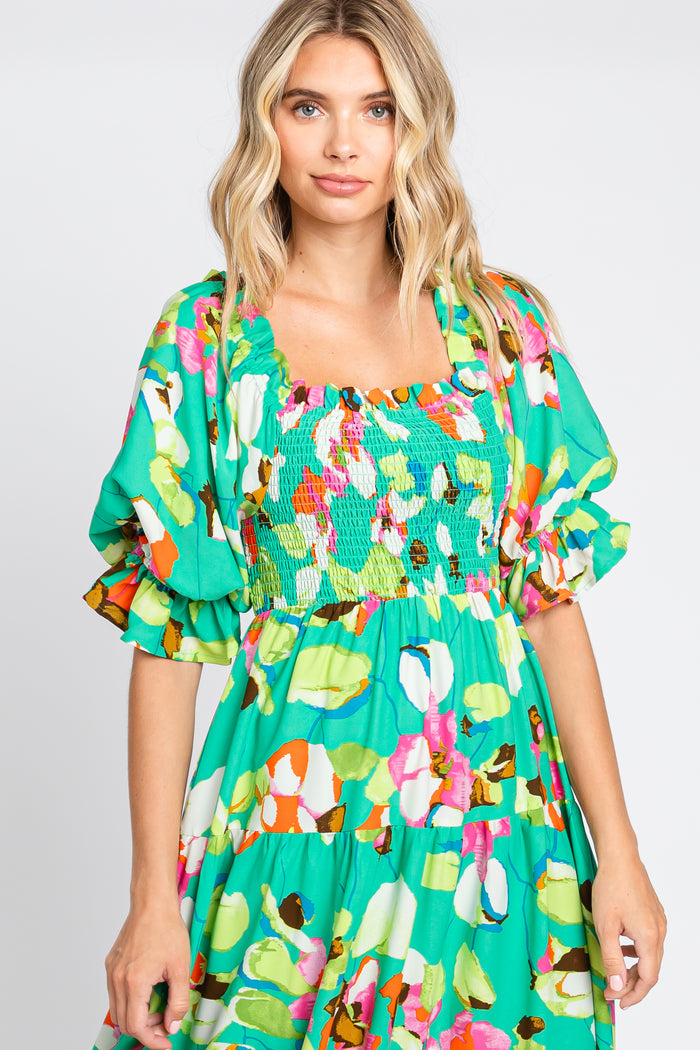 woman wearing a vibrant green floral dress with puff sleeves and a smocked bodice