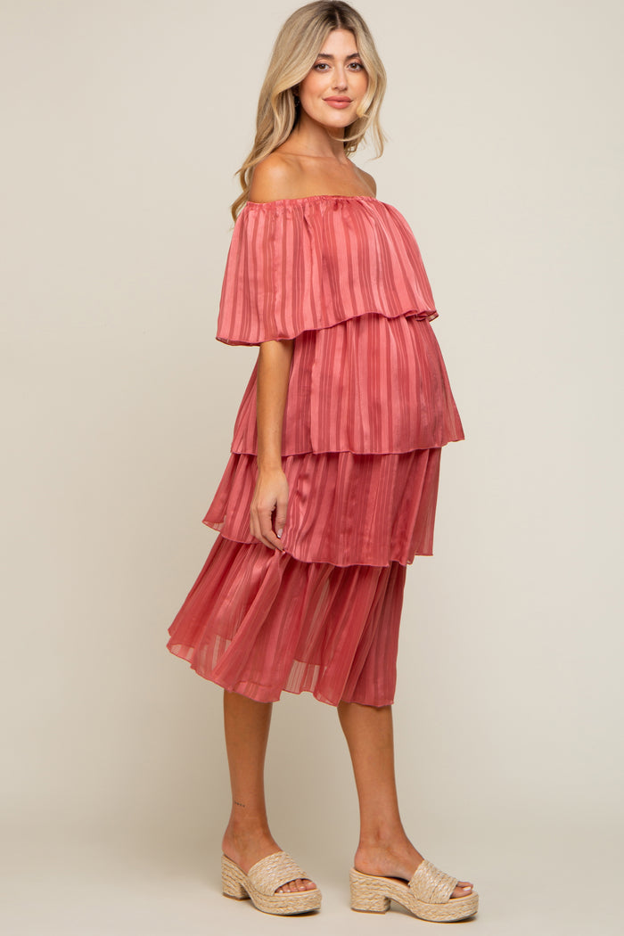 woman wearing a coral off-the-shoulder tiered maternity dress with a visible baby bump and strappy sandals