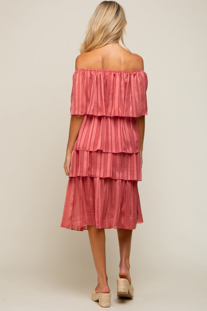 Back view of a woman wearing a rose pink off-the-shoulder tiered pleated midi dress with woven platform heels
