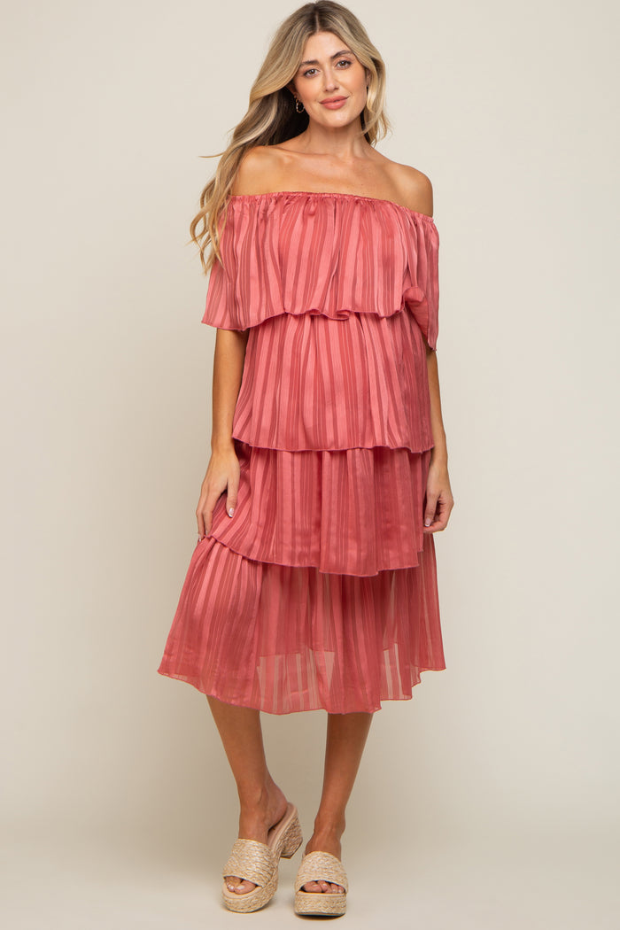 woman wearing a tiered off-the-shoulder maternity dress in a soft coral color with pleated fabric and a flowing silhouette