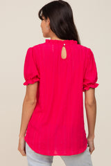 woman wearing a bright pink short sleeve blouse with a keyhole back and ruffle details