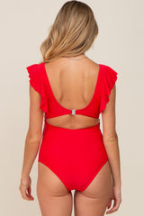 woman wearing a bright red maternity swimsuit with ruffle sleeves and a low back, showing her baby bump