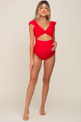 woman wearing a red maternity swimsuit with cut-out details and ruffled sleeves, showcasing her baby bump