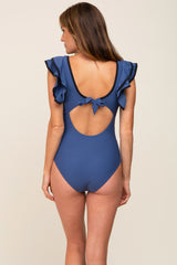 woman wearing a dark blue one-piece swimsuit with ruffle sleeves and an open back detail