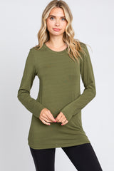 woman wearing an olive green long sleeve top paired with black leggings